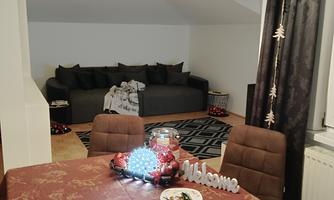 A cozy dining area with a table that is festively decorated. In the background, there is a comfortable couch and a beautiful curtain.