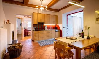 A bright kitchen with modern furniture and a dining area. The room has a friendly ambiance and wooden ceilings.