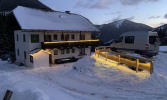 A cozy building in the snow with festive lighting. Snow-covered mountains are visible in the background.