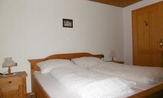 A cozy bedroom with a wooden double bed. Next to the bed are nightstands with lamps and there is a bright wooden ceiling.