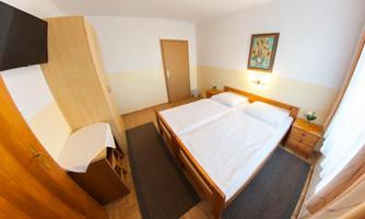 A simple room with two single beds. The room is bright and tidy, with a wooden wardrobe and a picture on the wall.
