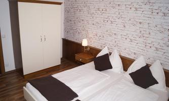 A cozy bedroom with two single beds and a modern wardrobe. The walls are designed in a stylish brick pattern.