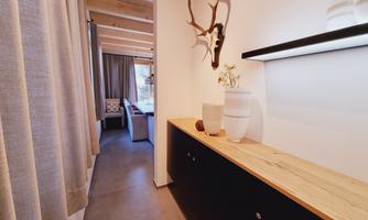 A modern hallway with an elegant wooden bench and decorative elements. In the background, living areas are visible that create a cozy atmosphere.