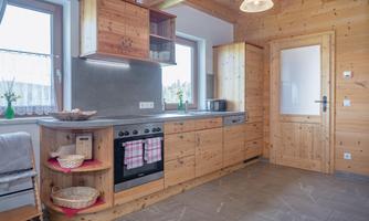 A modern wooden kitchen with bright walls and a cooking area. It is well-equipped and flooded with light.