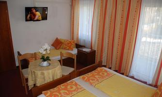 A cozy room with two beds and a small table. The walls are decorated with light fabric and colorful curtains.