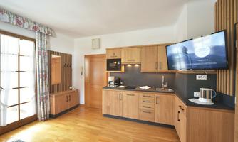 A modern kitchen with wooden cabinets and elegant design.  
Plenty of daylight pours in through the window that leads to the terrace.