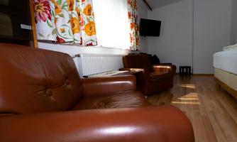 A cozy room with brown leather chairs and colorful curtains. A television can be seen in the background.