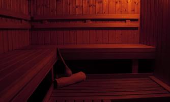 A cozy wooden sauna with warm light. The benches are empty and invite you to relax.