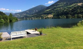 A tranquil lake with green meadows and gentle hills in the background. A wooden bench invites relaxation by the shore.