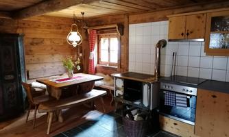 A cozy kitchen with wooden paneling and a large dining table. The decor exudes rustic charm.