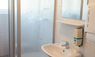 A modern bathroom with a shower cabin and a sink. The walls are brightly tiled, and there is a large mirror.