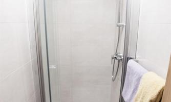 A modern shower with a glass partition and a towel. The walls are in neutral colors.