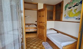 A simple room with wooden furniture and two beds. A painting of swans hangs on the wall.