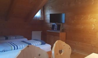 A cozy room with wooden walls and two beds. A table and a television are also present.