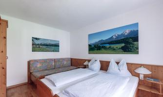 A cozy room with two beds and a sofa bed. Pictures of a picturesque landscape hang on the wall.