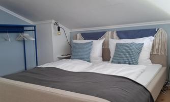 A modern bedroom with a comfortable bed and decorative pillows. The walls are painted in light colors, creating a calming atmosphere.