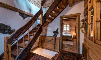 A cozy wooden staircase leads upstairs. The room has rustic elements and an inviting atmosphere.