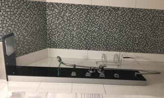 A modern shower with shiny tiles and a rain shower head. The walls are designed with black and white mosaic tiles.