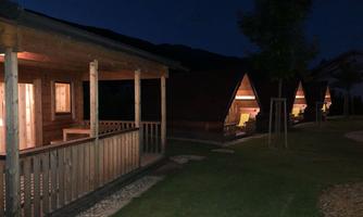 Cottages at night, illuminated and surrounded by grass and trees. The atmosphere is calm and inviting.