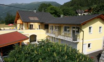 A cozy building set in a picturesque mountain landscape. The houses are surrounded by trees and green spaces.
