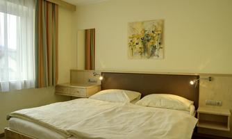 A cozy bedroom with a double bed and warm colors. A beautiful painting hangs on the wall, and the window allows for plenty of daylight.
