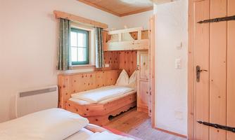 A cozy room with wooden paneling and a bunk bed. A large window lets in plenty of daylight.