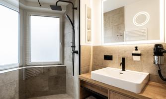 A modern bathroom with an elegant shower and large windows. The ceramic sink sits on a wooden shelf.