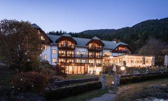 A charming hotel with cozy lighting at dusk. Surrounded by mountains and a well-kept garden.