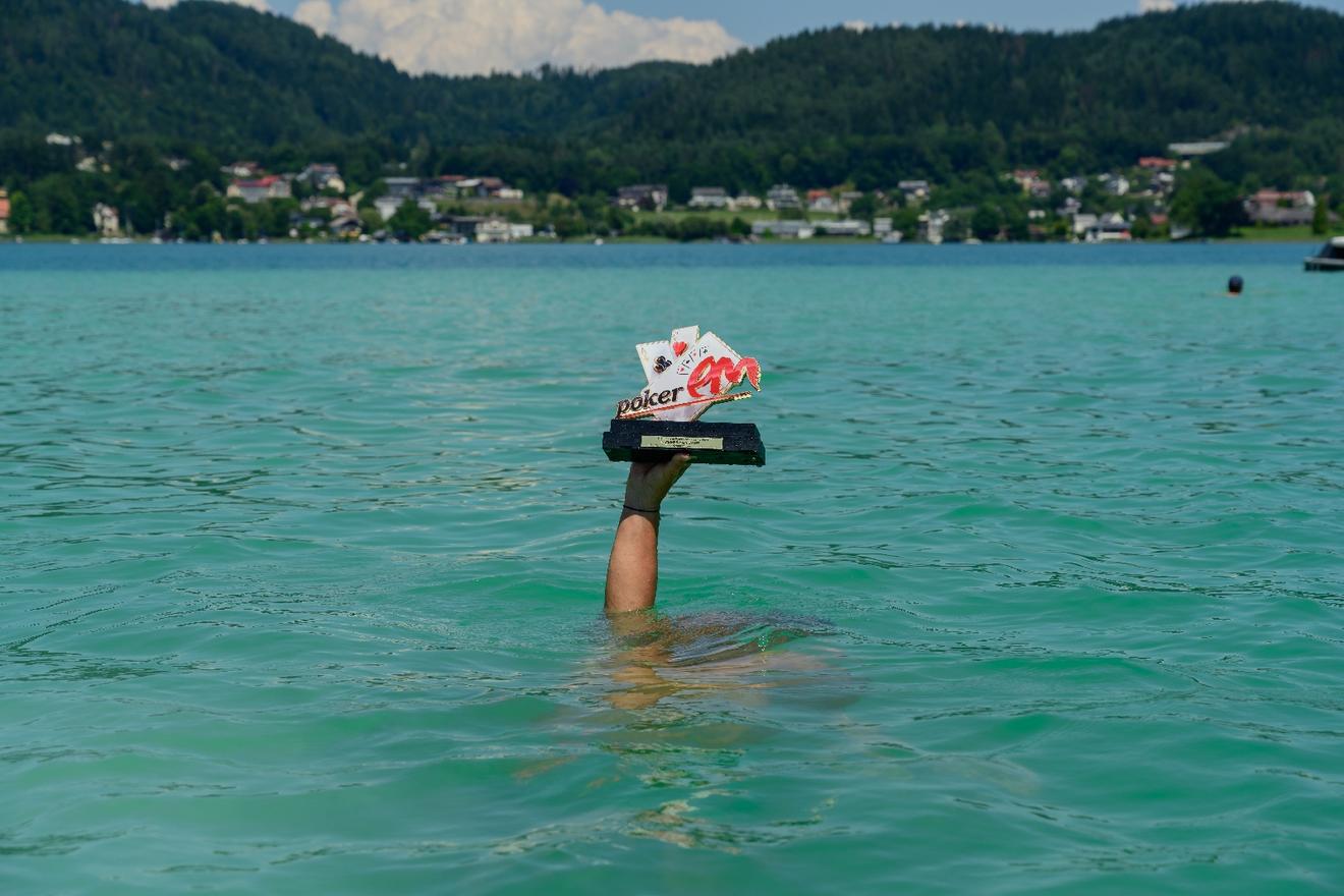 Poker-Trophäe wird im türkisfarbenen Wasser des Wörthersees in Kärnten hochgehalten