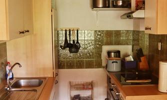 A bright kitchen with a wooden ceiling and modern appliances. The walls are in soft tones and the furniture is made of light wood.