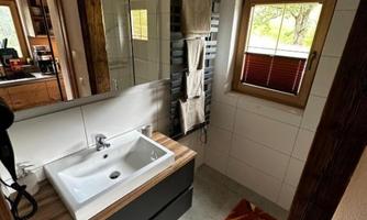 A modern bathroom with a white sink and wooden details. The window provides natural light and a cozy atmosphere.