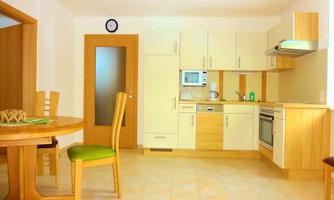 A bright kitchen with light wooden furniture and modern appliances. The dining area is cozy with a round table and chairs.