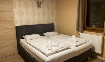 A cozy bedroom with a large double bed and modern furniture. The walls are painted in warm colors and the windows let in plenty of daylight.