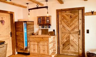 A cozy kitchen with wooden furniture and a blue refrigerator. The walls are bright, and there are rustic wood details.