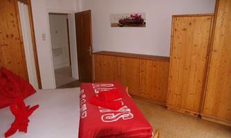 A simple room with wooden furniture and a comfortable bed. On the bedspread, a red pillow lies decoratively.