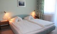 A cozy bedroom with two beds and bright light. The walls are painted in soft color tones.