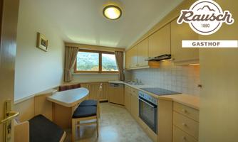 A bright kitchen with modern furniture and a large window that offers a beautiful view. The room is cozy and functionally furnished.