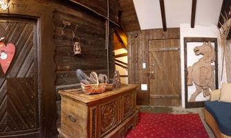 An inviting hallway with rustic wooden doors and a cozy seating area. A decorative horse painting can be seen on the wall.