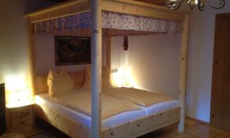 A cozy bedroom with a wooden canopied bed. Soft light creates an inviting atmosphere.
