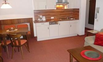 A cozy kitchen with a dining area and wood-paneled walls. The decor is bright and inviting.