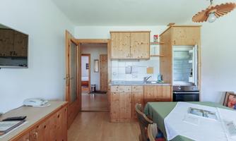 A cozy kitchen with wooden furniture and a dining area. The rooms are bright and inviting.