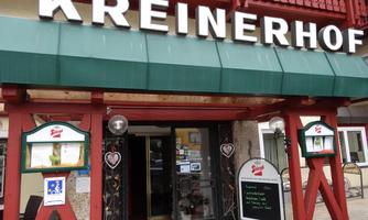 An inviting inn named "Kreinerhof." The facade is red and white with a green roof and two menu signs.