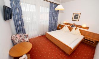 A cozy bedroom with a double bed and a beautiful view out of the window. The room is brightly and cheerfully decorated, with a small table and chairs.
