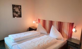 A cozy bedroom with two beds and warm light sources. On the wall hangs a beautiful picture of flowers.