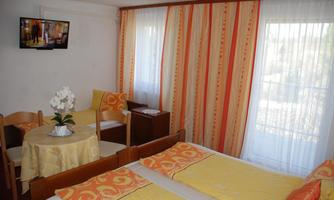 A cozy room with two beds and yellow bed covers. It includes a table with chairs and a television on the wall.