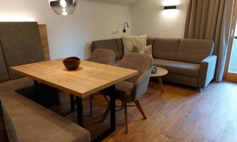 A modern living room with a cozy seating area and a wooden dining table. The warm colors and the pleasant lighting create an inviting atmosphere.