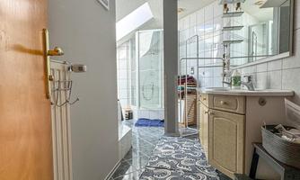 A modern bathroom with a long rug and bright tiles. On the right side, there is a sink with a mirror and cabinets.