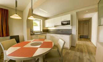 A modern kitchen with a round table and four chairs. The walls are bright and the furnishings are functional and stylish.