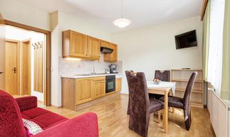 A modern kitchen with wooden furniture and a dining area. The room has a cozy style and plenty of daylight.