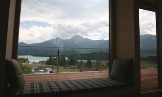 A beautiful view of mountains and a lake. The sky is overcast and there is a cozy windowsill.